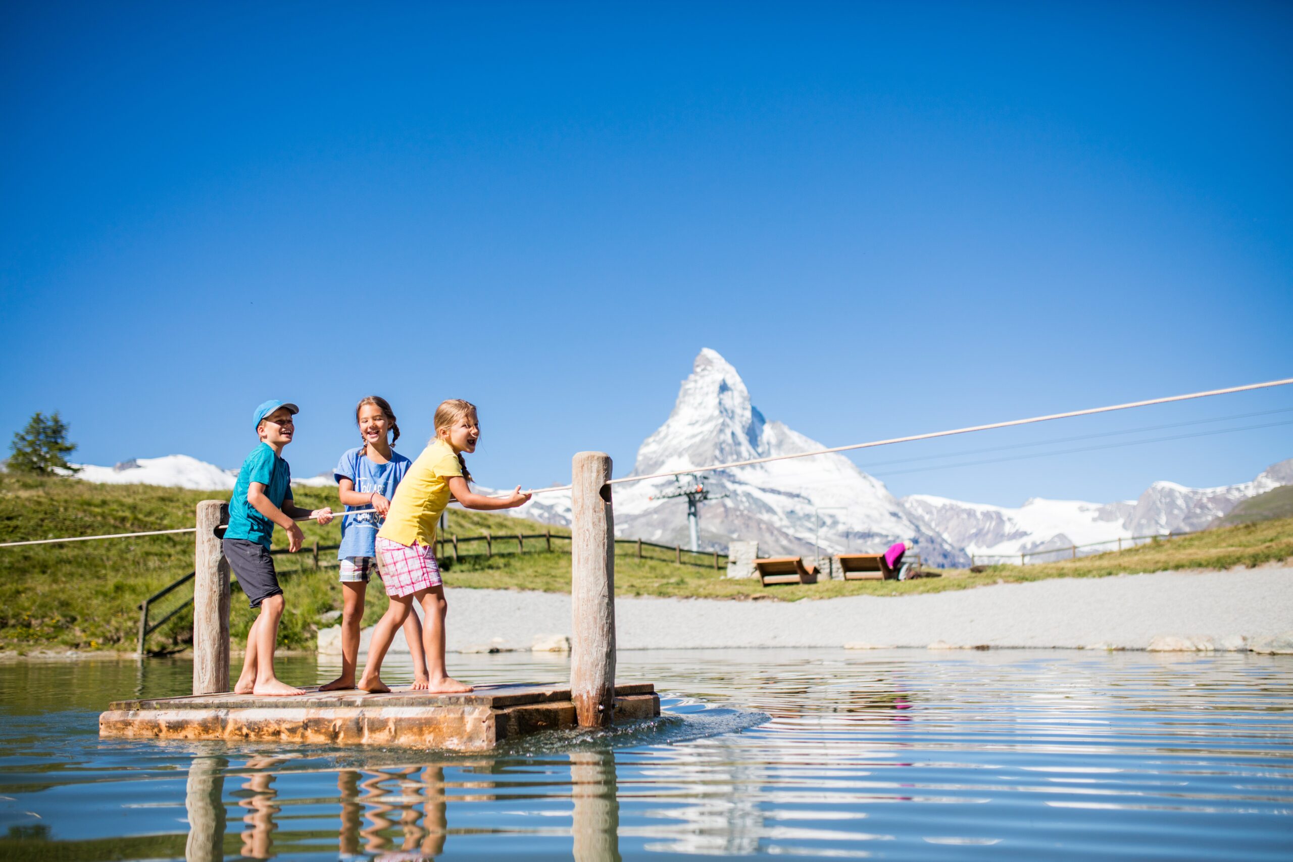 Kinder spielen am Bergsee mit Spielplatz in Zermatt